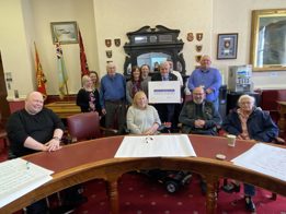 People sitting around a table, holding up the disability impact pledge.