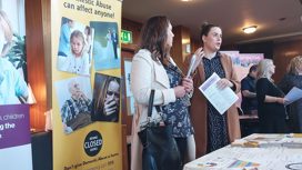 People holding leaflets from a stall about domestic abuse.