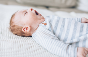 baby yawning on white blanket