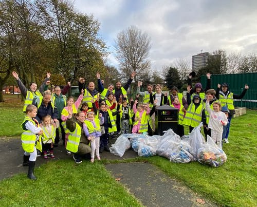 A group of people posing behind bags of litter they've collected.